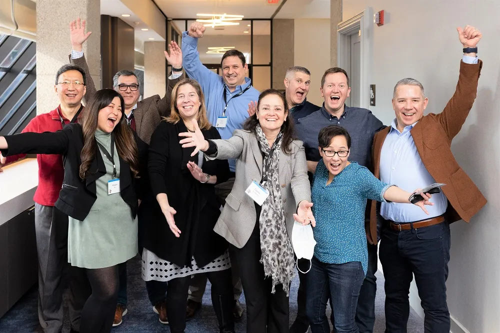 group of adlut professionals smiling standing in the hall way with outstretched arms having fun