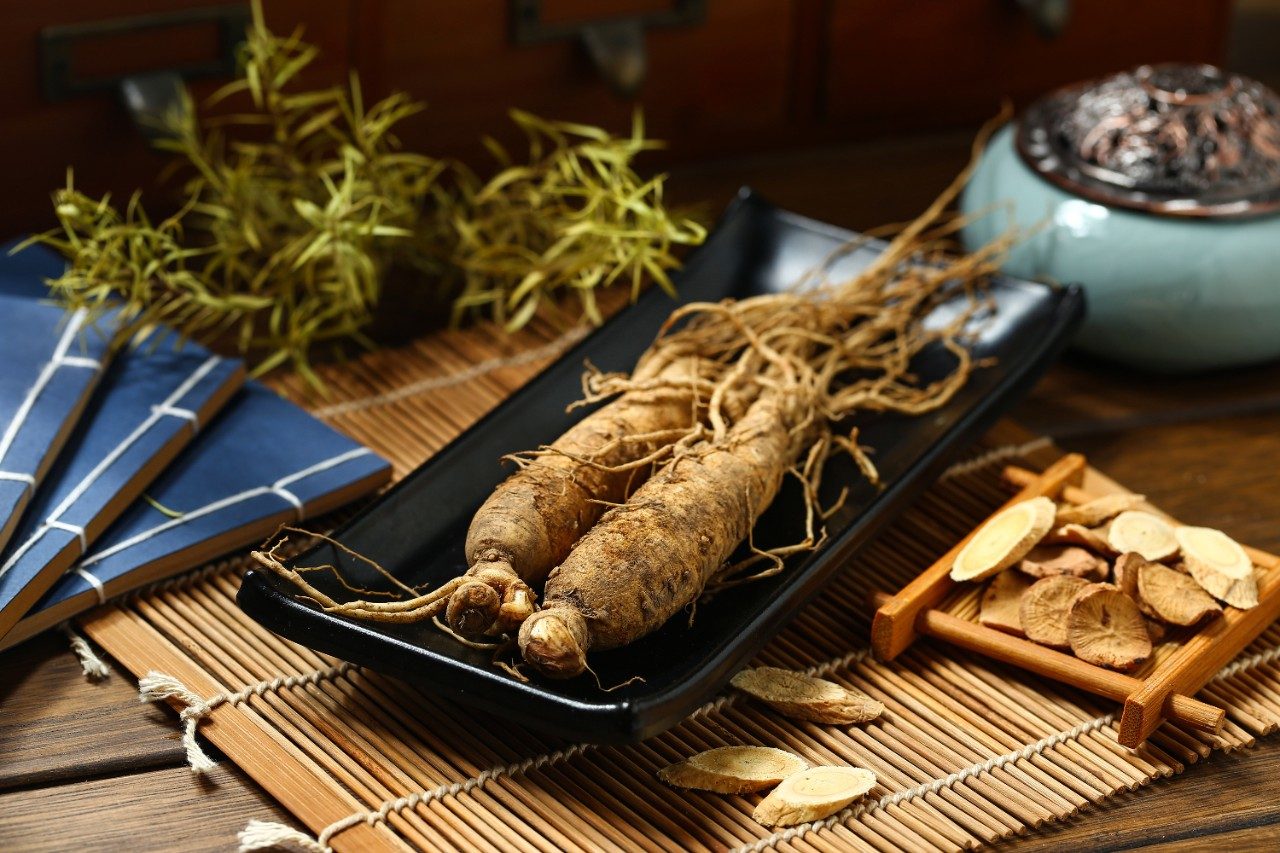 Ginseng root on black plate on wooden table