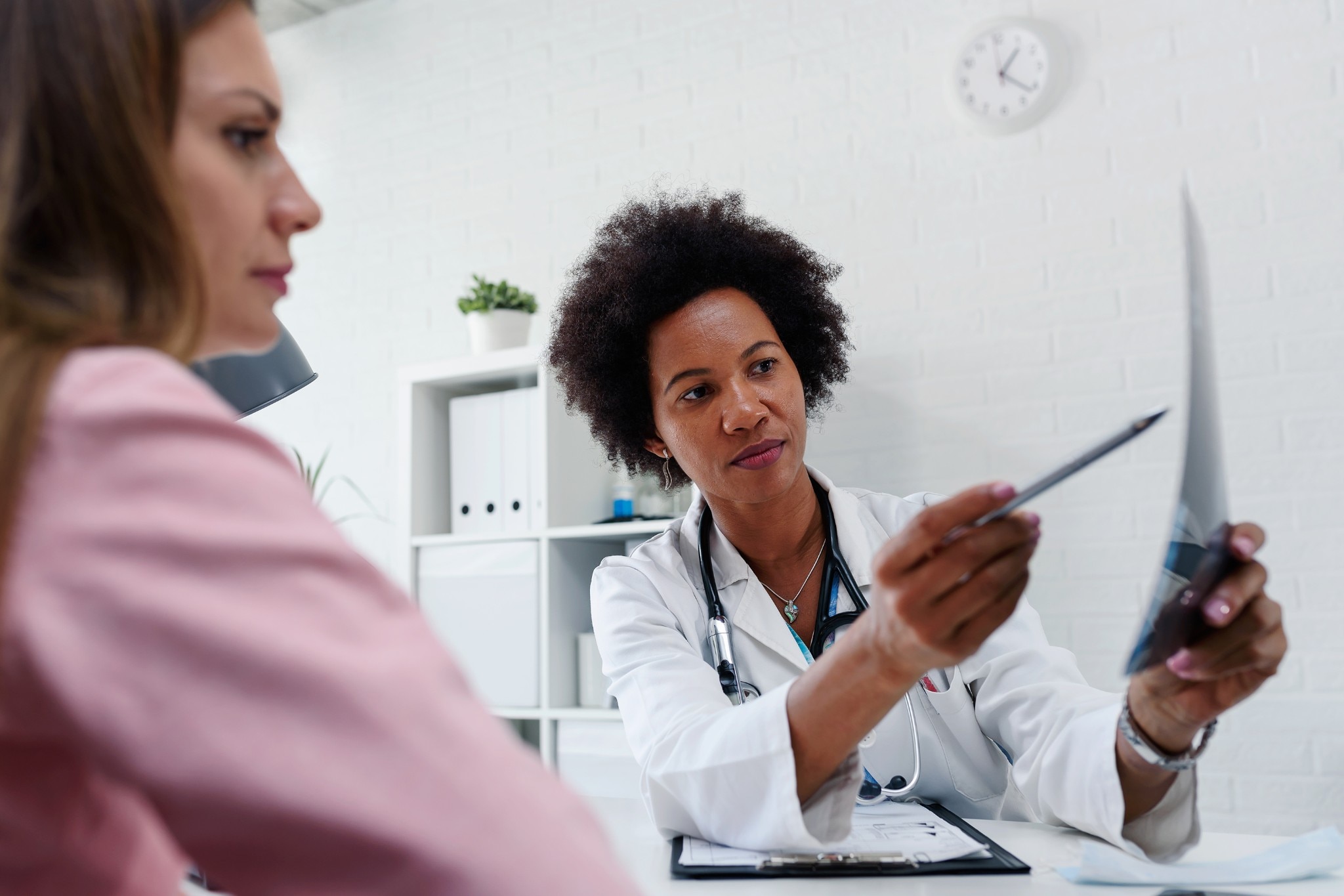 Doctor talking with patient at desk in medical office - Women's Health