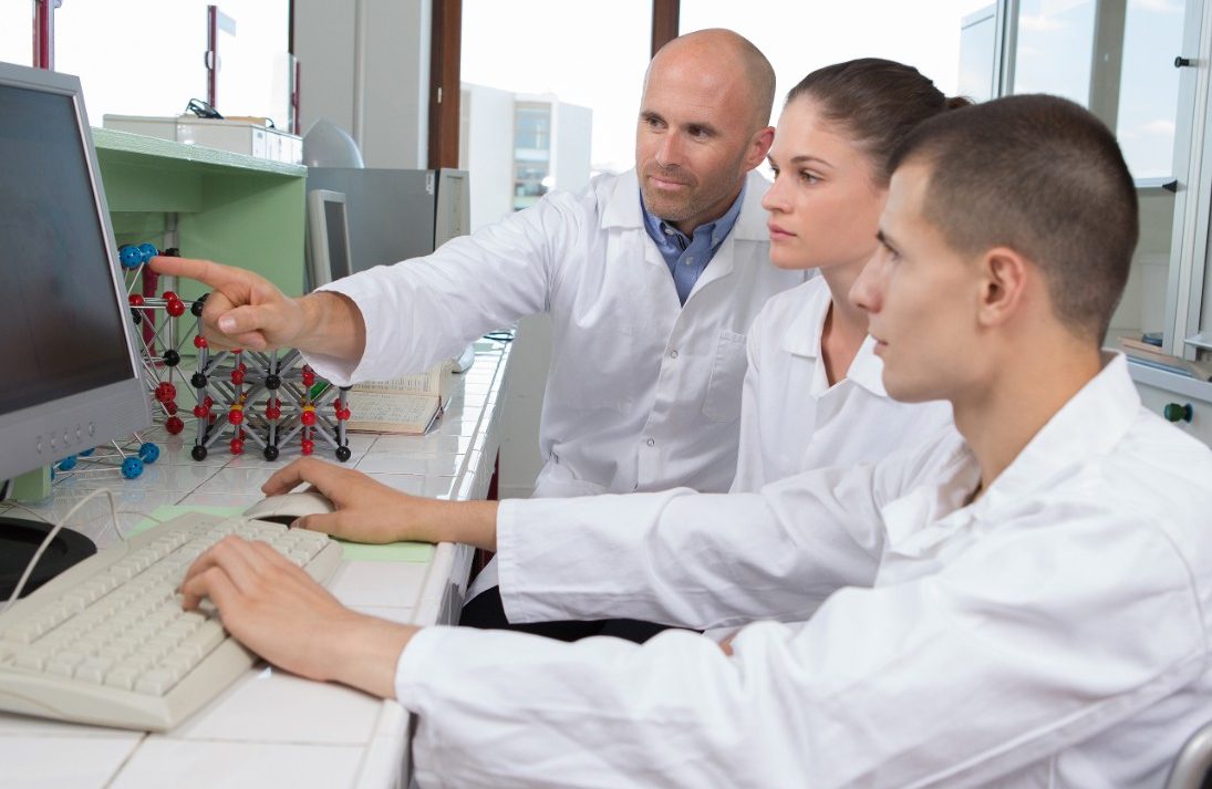 Three scientists researchers reviewing data on monitor