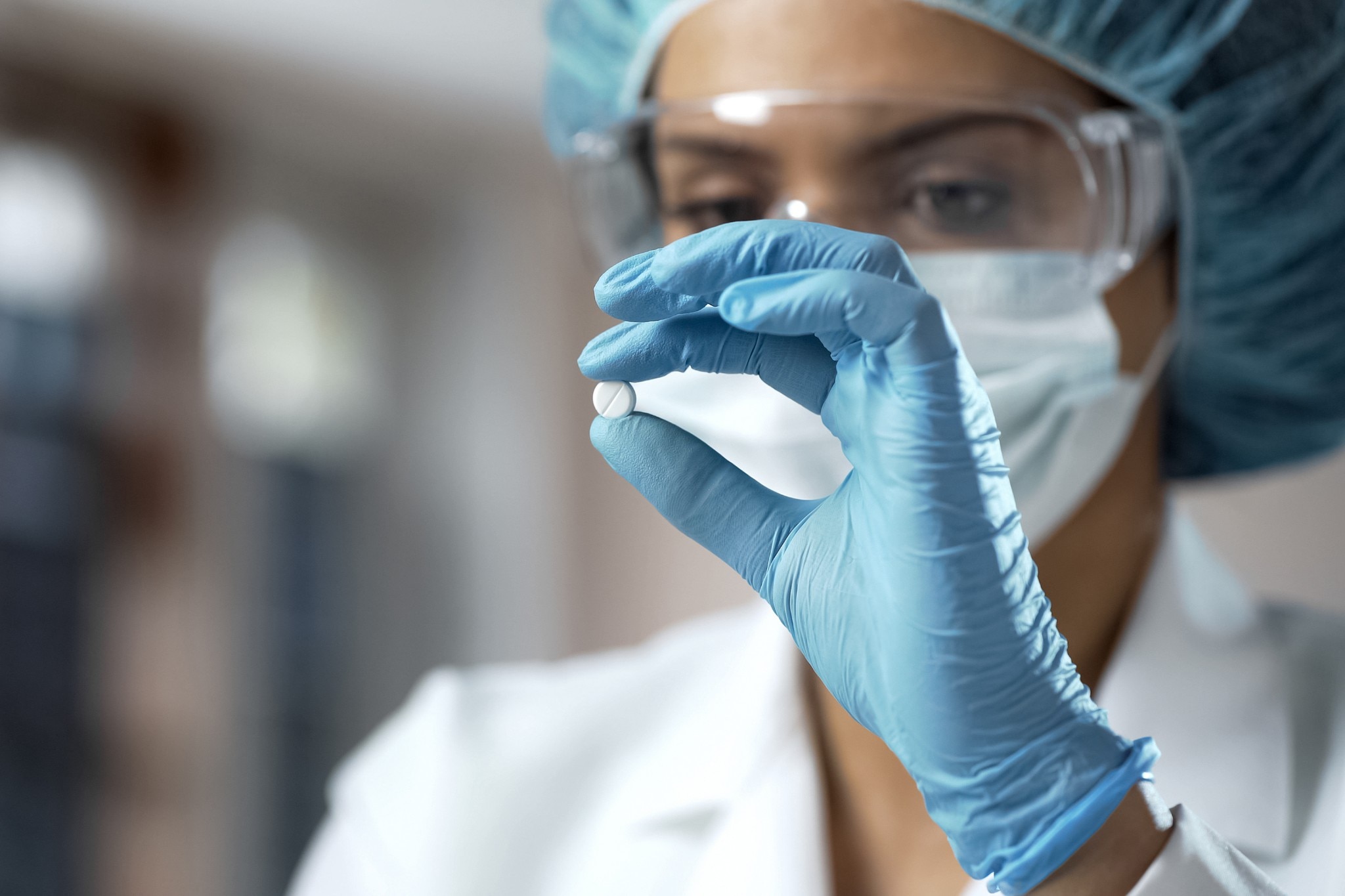 Mujer químico mirando una pastilla blanca, análisis de nuevo medicamento en el laboratorio